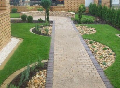 Ścieżka ogrodowa z kostki brukowej w zieleni.